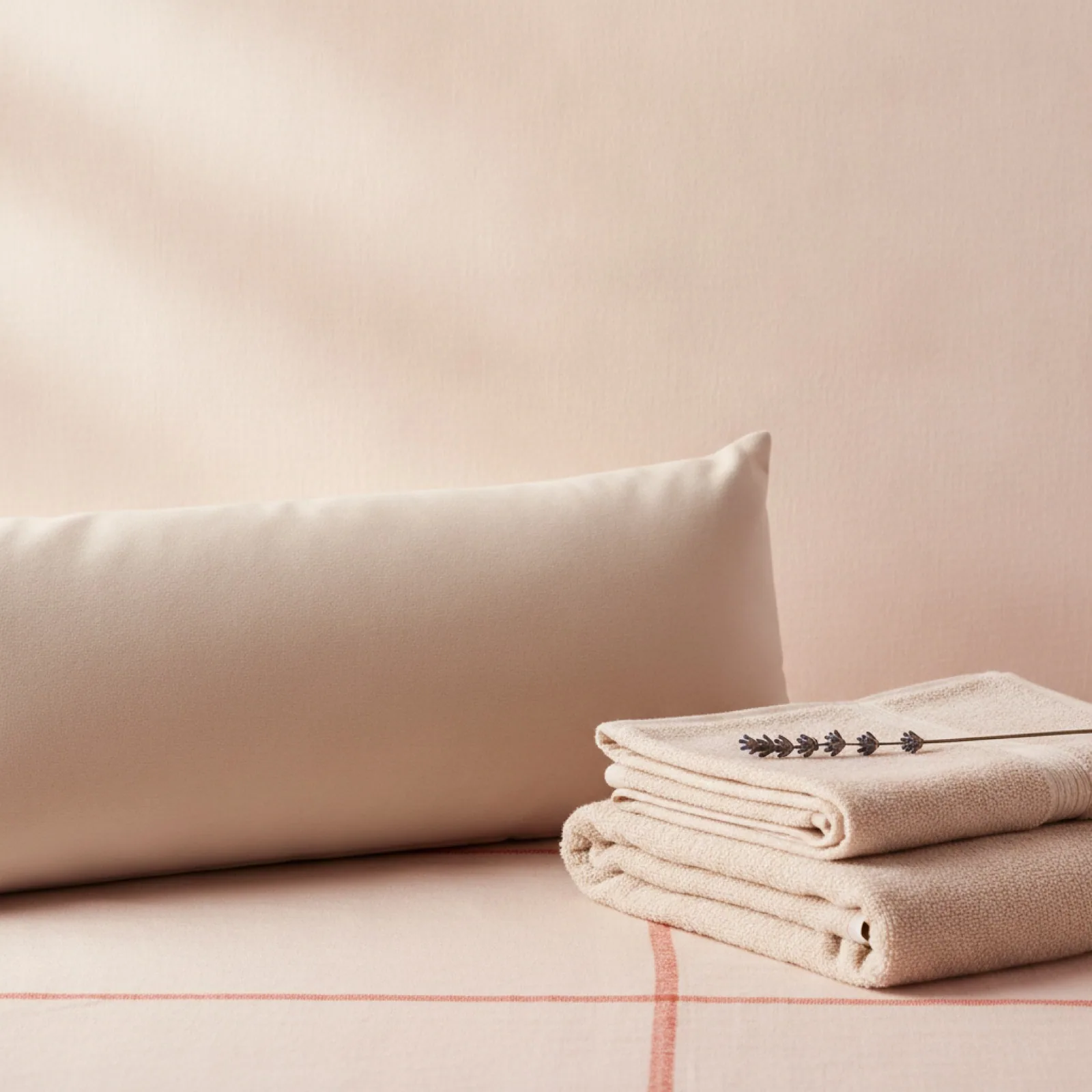 A soft bolster and folded towels on cream linen — stylized imagery